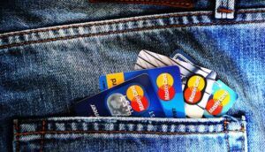 Several credit cards sticking out of a blue denim jean pocket