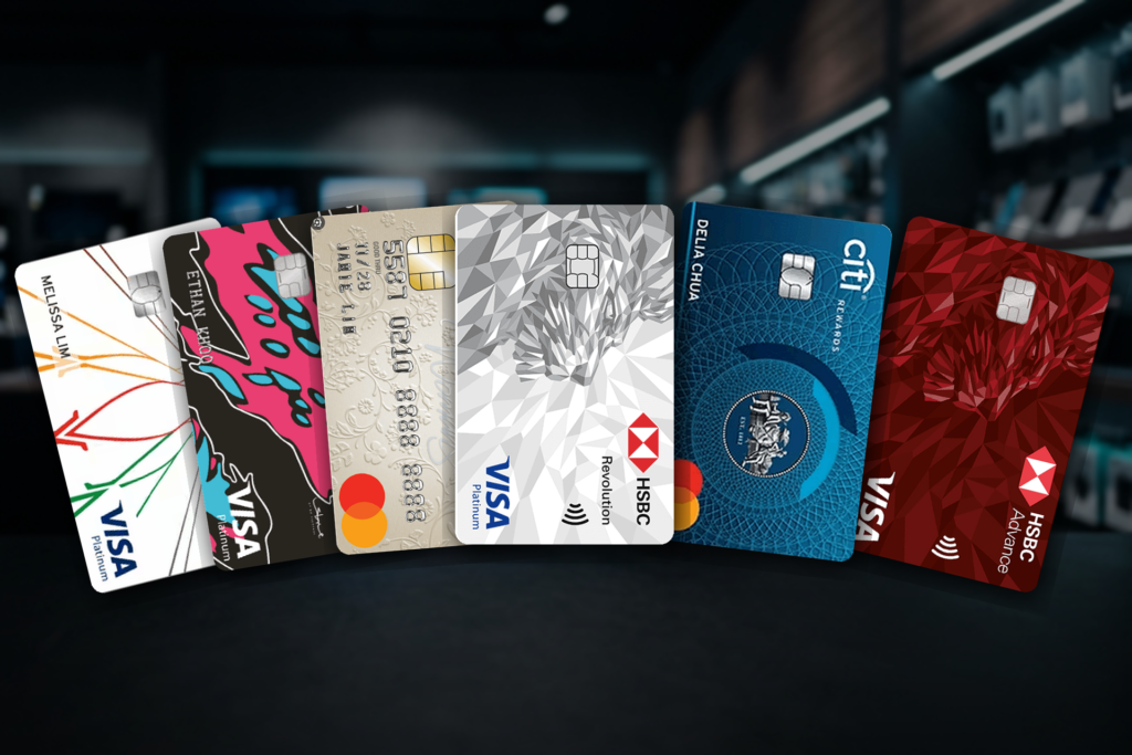 Best credit cards for electronics purchases in Singapore — HSBC Revolution, DBS Woman's World, Citi Rewards, DBS Live Fresh, HSBC Advance and Citi SMRT credit cards fanned over an electronics-store background